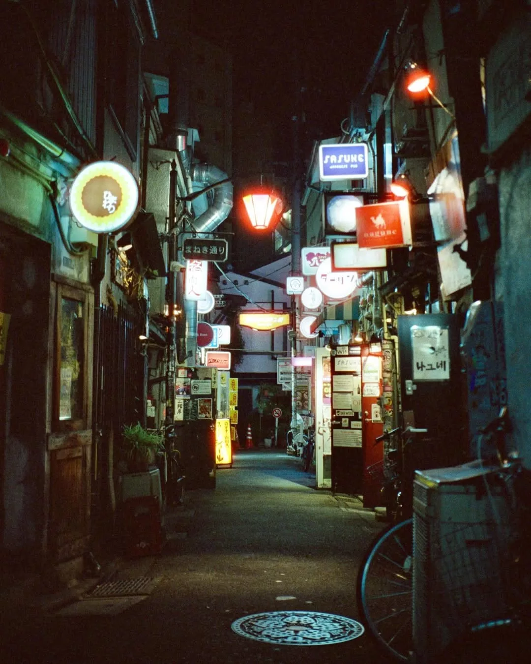 Narrow alley at night lined with glowing signs, CineStill 800T, Leica M6, by @tywright95
