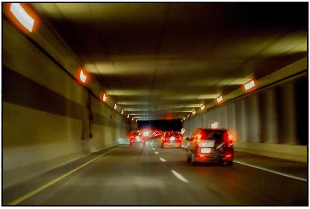 Cars in a tunnel with glowing red taillights, CineStill 800T, Minolta XG-M, by @stevedascher