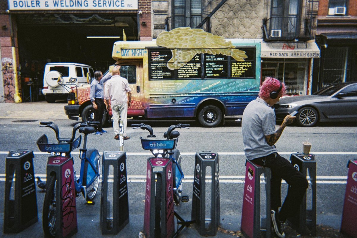 New York street scene with bike-share dock and painted bus, shot on a Gelatin disposable camera