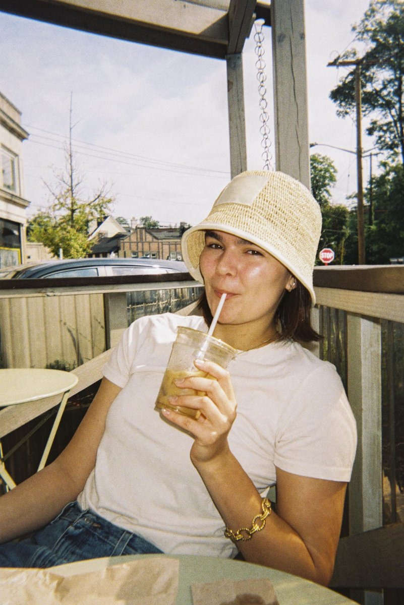 Friend sipping iced coffee on a porch, shot on a Gelatin disposable camera