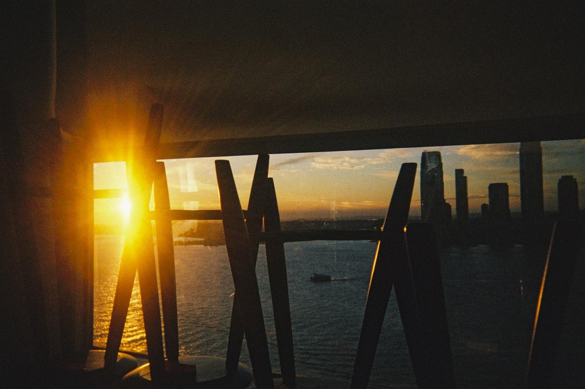 Harbor sunset through barstool legs with the Jersey City skyline, shot on a Gelatin disposable camera. Photo by Nick Thomsen.