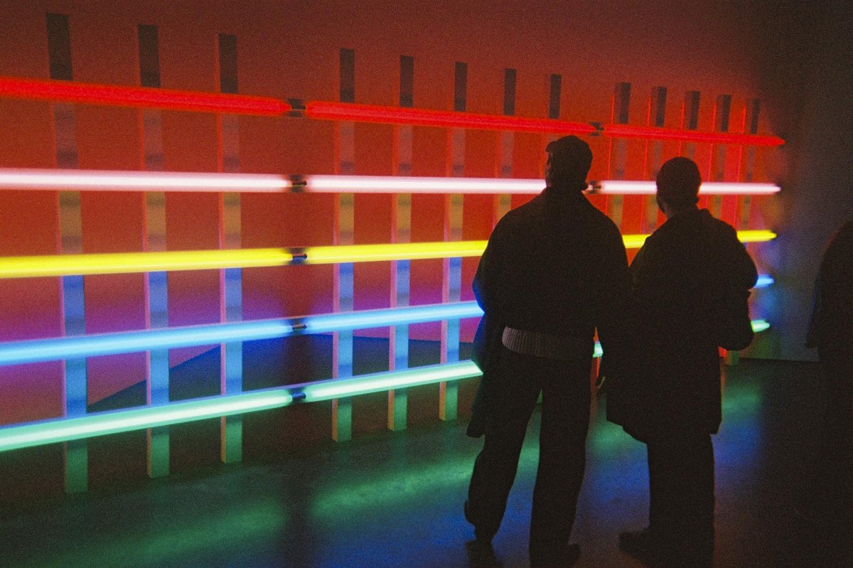 Two silhouettes in front of a neon light installation, shot on a Gelatin disposable camera. Photo by Nick Thomsen.